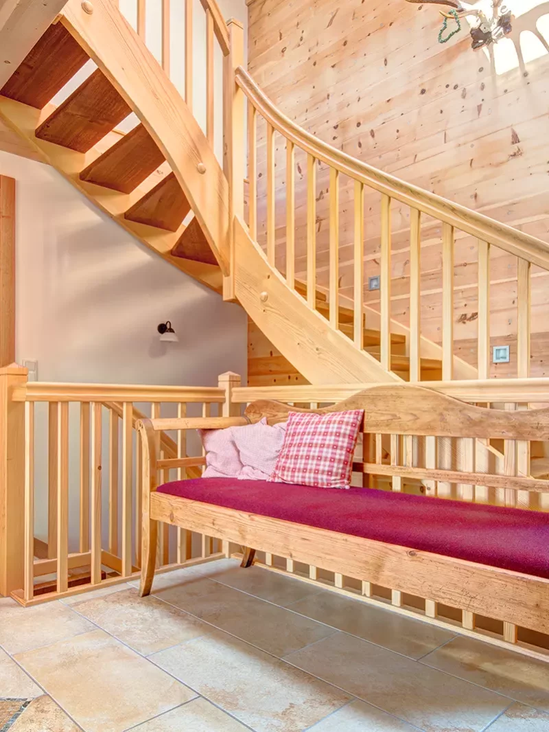 Eingangsbereich in einem Holzhaus mit Zirbenwand und Treppe