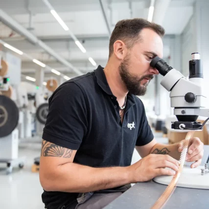 Mann überprüft Bauteil mit Mikroskop